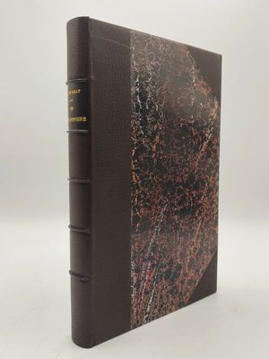 un livre brun posé sur une table à côté d'un mur blanc