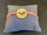 un gros plan sur un petit oreiller sur lequel est posé un bracelet jaune et orange