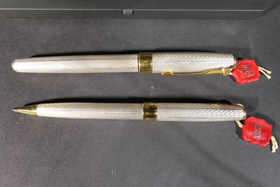 two pens sitting on top of a black surface next to a box