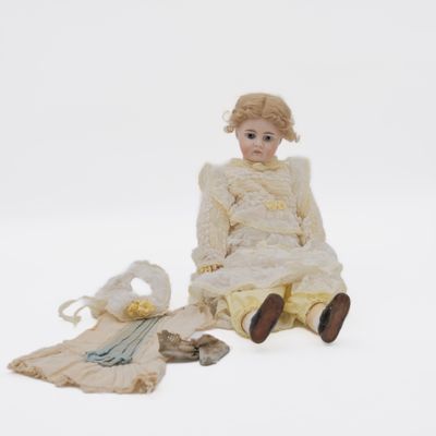 a doll that is sitting on the ground next to a bag