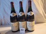Trois bouteilles de vin sont posées sur une table, accompagnées d'une étiquette de prix