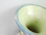 a green and blue vase sitting on a white table