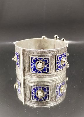 un gros plan sur un bracelet en argent orné de motifs bleus et blancs