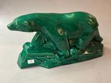 une statue verte représentant un ours polaire perché sur un rocher