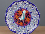 assiette décorative bleue et rouge ornée d'un oiseau, posée sur une table en bois