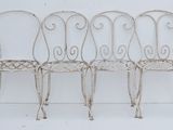 three white wrought chairs sitting next to each other on a white surface