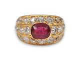 gros plan d'une bague en or avec un rubis et un diamant au centre