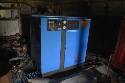 a blue air compressor sitting in a room with other equipment