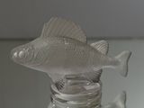 a glass bottle with a fish in it on a table