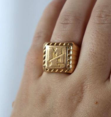 quelqu'un tient une bague en or sur laquelle figure un chiffre romain