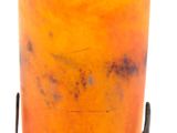 an orange vase with a metal stand on a white background
