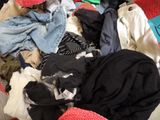a pile of clothes on a bed with a hat on