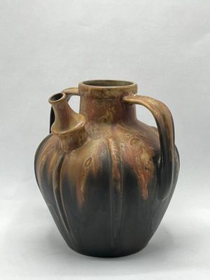 a brown vase that is sitting on a white surface