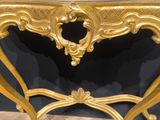 an ornate gold console table with marble top on a wooden floor