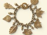 an image of a gold bracelet with charms and leaves