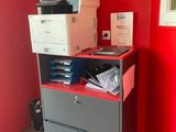 un mur rouge dans un coin d'une pièce, avec une imprimante posée sur un classeur