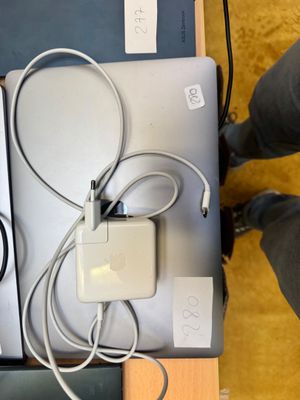 une personne debout à côté d'une table sur laquelle se trouvent un ordinateur portable et un chargeur