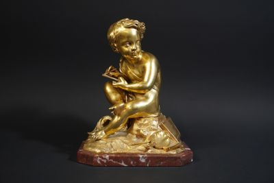 a gold figurine of a boy sitting on a rock