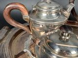 a silver tea set on a silver tray with a wooden handle