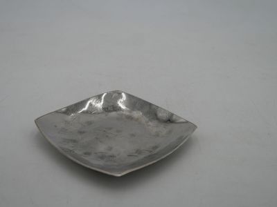 a small silver plate on a table with a white background