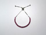 a close up of a red beaded bracelet on a white surface