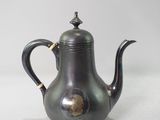 an antique silver tea pot on a white surface