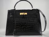 un sac à main en cuir de crocodile noir avec des finitions dorées sur la poignée