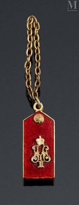 a close up of a red and gold dog tag with a gold chain
