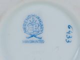 a close up of a white plate with a blue flower on it