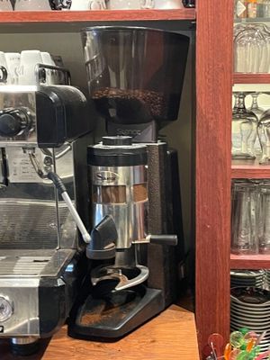 a coffee maker and cups on a shelf in a kitchen