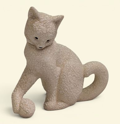 une petite statue représentant un chat assis sur une surface blanche