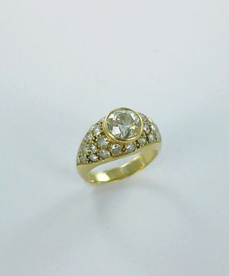 gros plan d'une bague en or avec des diamants sur une surface blanche