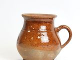 a brown cup that is sitting on a white surface