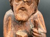 wooden statue of an old man with a beard and hat holding a stick