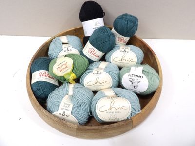 many balls of yarn in a wooden bowl on a table