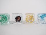 quatre cubes de verre de couleurs différentes posés sur une surface blanche