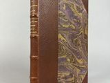 un livre en cuir marron dont la couverture marbrée se détache sur un fond blanc