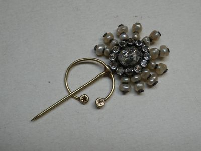 a brooch with pearls and a pin on it