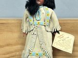 an image of a doll of a native american woman holding a sign