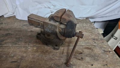 an old vise on a wooden table with a white sheet