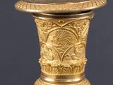 a gold vase with a design on the top of it