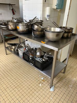 de nombreuses casseroles et poêles posées sur une table dans la cuisine