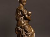 a bronze statue of a woman holding a baby on a wooden table