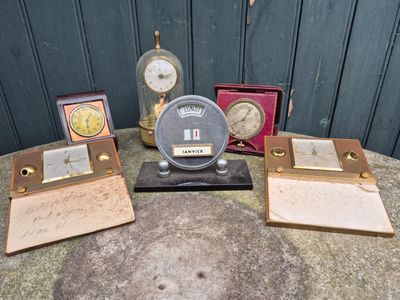 five different clocks sitting on a table next to each other