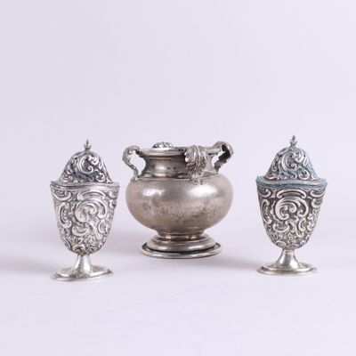trois vases en argent posés l'un à côté de l'autre sur une surface blanche