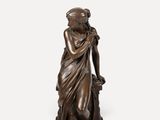 une statue en bronze représentant une femme tenant un panier