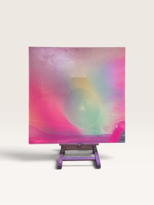 une peinture abstraite posée sur un chevalet, sur fond rose et bleu
