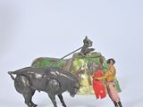 a figurine of a man riding a bull next to a statue of a bull