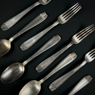 beaucoup de cuillères et de fourchettes en argent posées sur une table noire