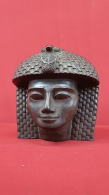 un gros plan sur une sculpture représentant une tête de femme posée sur une surface rouge